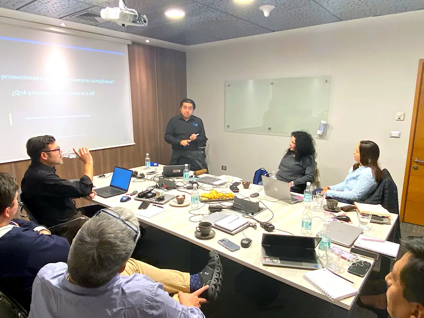Equipo de Think4Change reunido en un taller de trabajo, dialogando alrededor de una mesa en un ambiente industrial con una sensación colaborativa y enfocada
